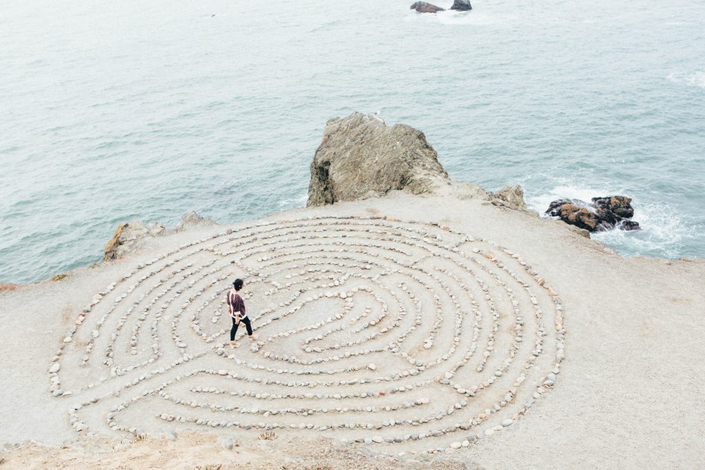 Küstenszenerie: Weißes Felsplatteau mit flachem Labyrinth vor blauem Meer