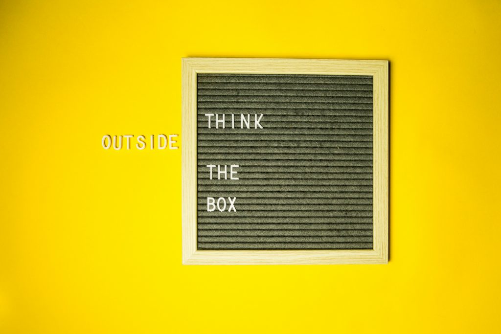 Tafel mit dem Text "think outside the box", wobei das Wort "outside" außerhalb des Tafelrahmens platziert ist